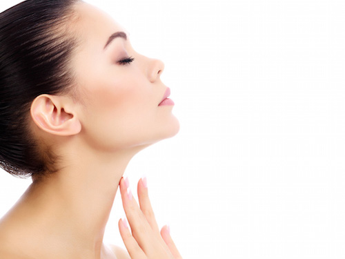 Young female touches her neck, white background, copyspace
