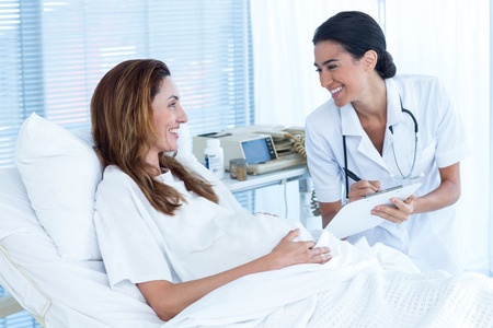 42577663 - smiling pregnant woman with her doctor in hospital room