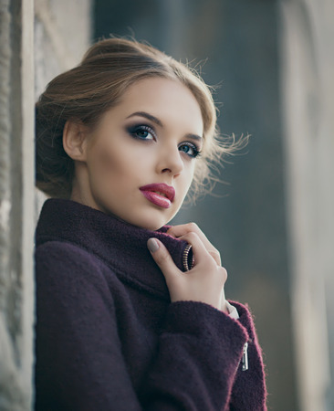 29953668 - beautiful woman with bright makeup wearing a warm jacket in the street