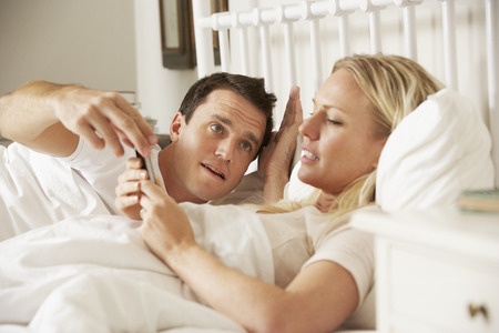 42269920 - husband complaing as wife uses mobile phone in bed