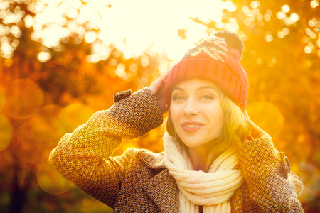 43393739 - young woman in beanie hat on autumn background in sunny day. smiling happy girl portrait. toned photo with bokeh and copy space.