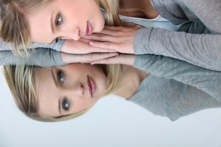 12529500 - blonde woman looking her reflection in a mirror