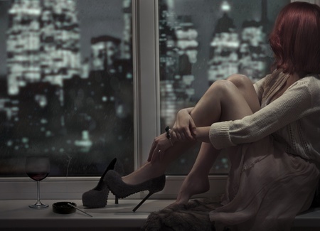 12638673 - alone beautiful woman sitting on window and looking on night city