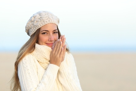 34326659 - woman warmly clothed in a cold winter on the beach with the sky in the background