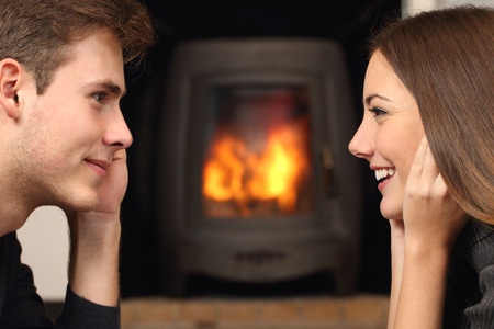 37232672 - side view of a couple flirting and looking each other in front a fireplace