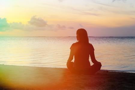 44588740 - young woman meditation on sunset tropical beach