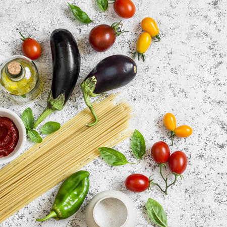 62090655 - raw ingredients for making pasta - spaghetti, eggplant, tomatoes, pepper, olive oil, tomato sauce and basil . cooking background, top view