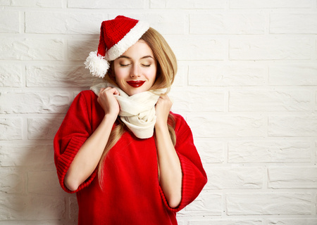 49230538 - smiling christmas girl with closed eyes in red winter clothes at white brick wall background. romantic dreaming woman portrait. toned photo with copy space.